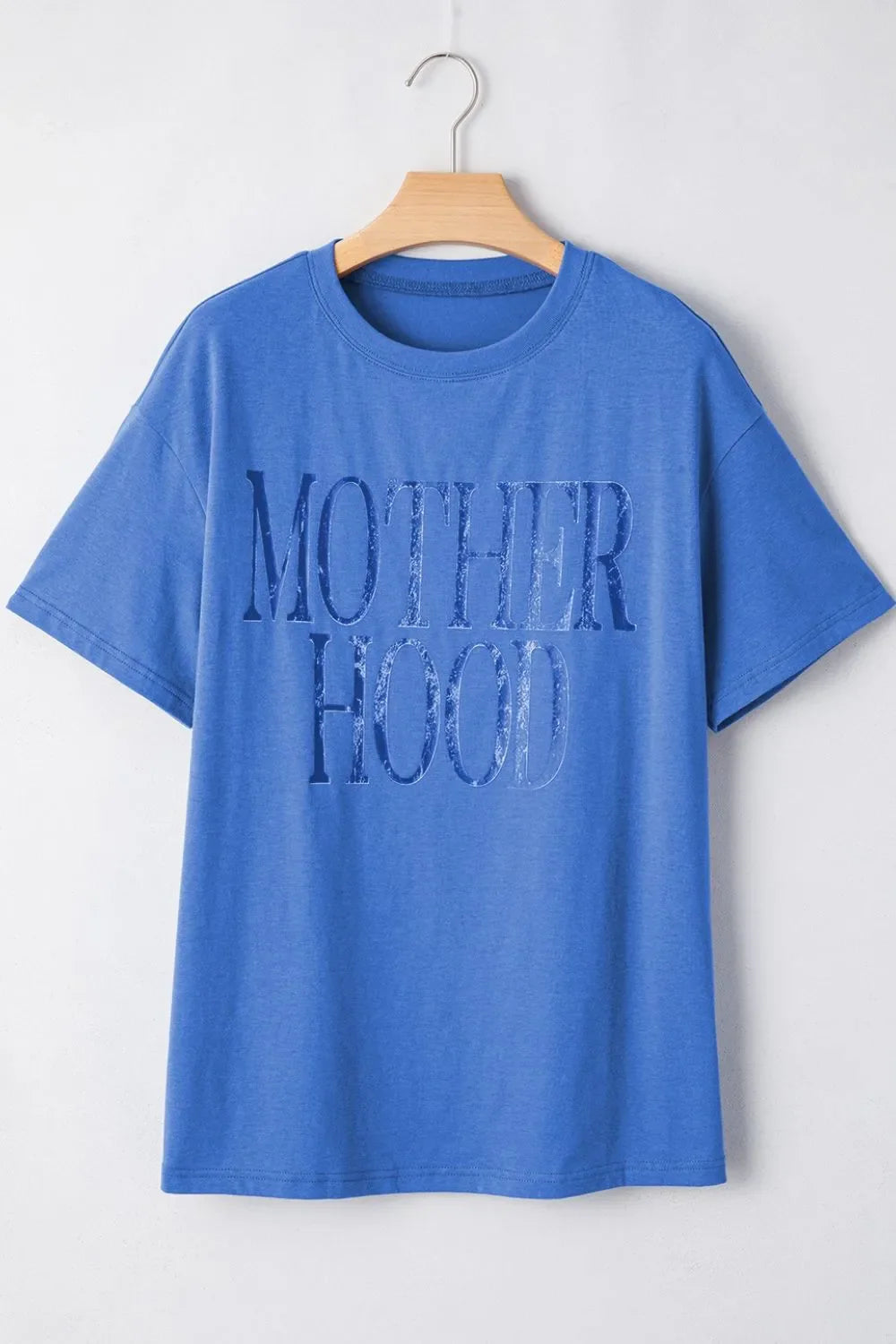 Blue oversized graphic t-shirt with "MOTHERHOOD" text