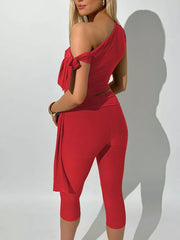 Red asymmetrical one-shoulder top with tie detail and capri pants ensemble.