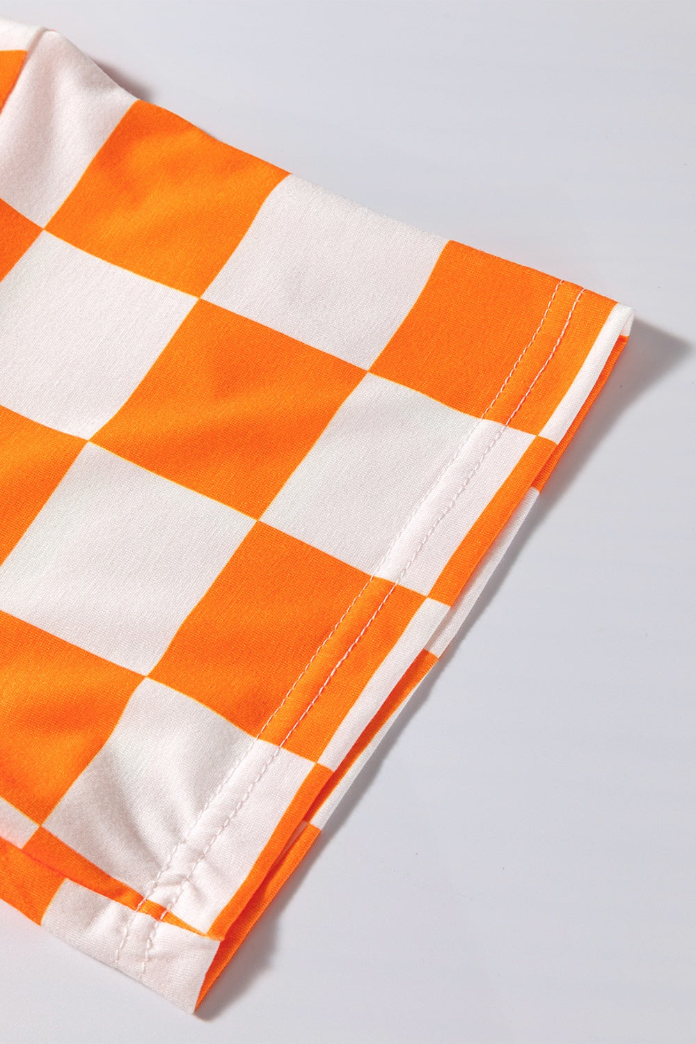 Orange and white checkered outfit set detail showing hem stitching