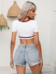 White cable-knit crop top with short sleeves and maroon trim.