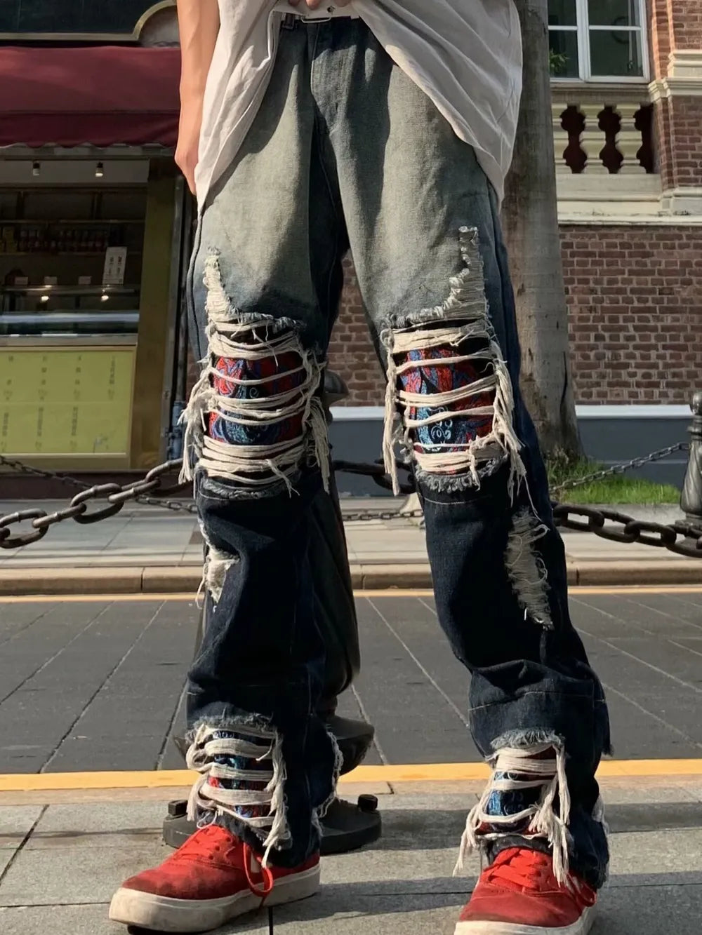 Loose fit distressed jeans with two-tone denim and patterned patches.