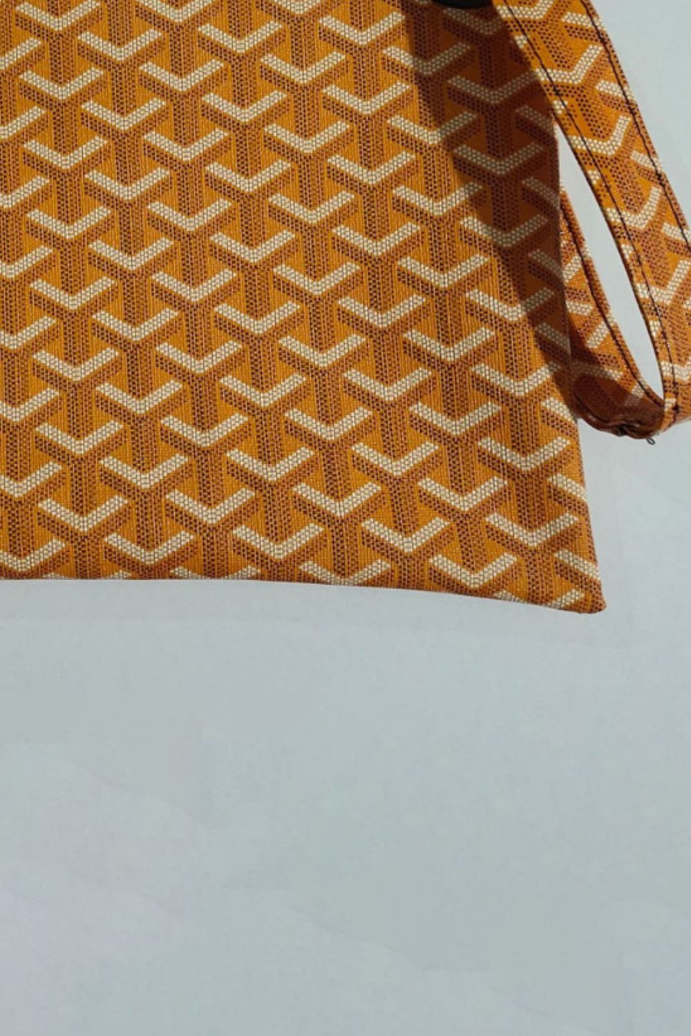 Tangerine plaid print wristlet clutch bag with geometric pattern and wrist strap.