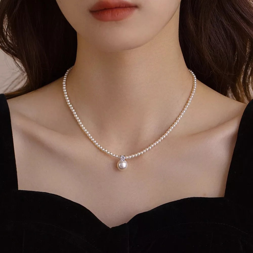 Luminous pearl pendant choker necklace with delicate chain and crystal accent.