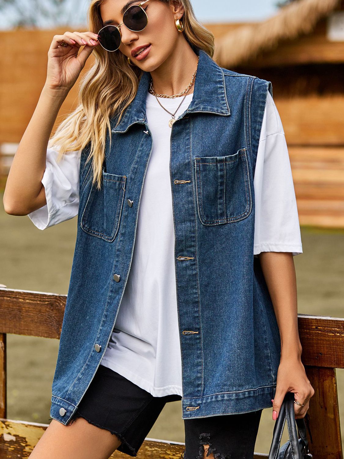 Sleeveless denim utility vest in dark gray with button front and chest pockets.