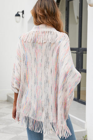 Textured knit cape in ivory with multicolor stripes and fringe trim.