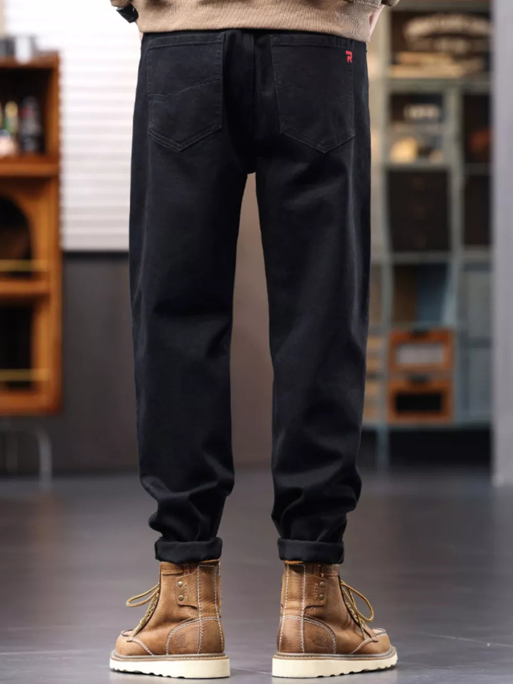 Men's black relaxed fit cotton jeans with drawstring waist and cuffed hems.