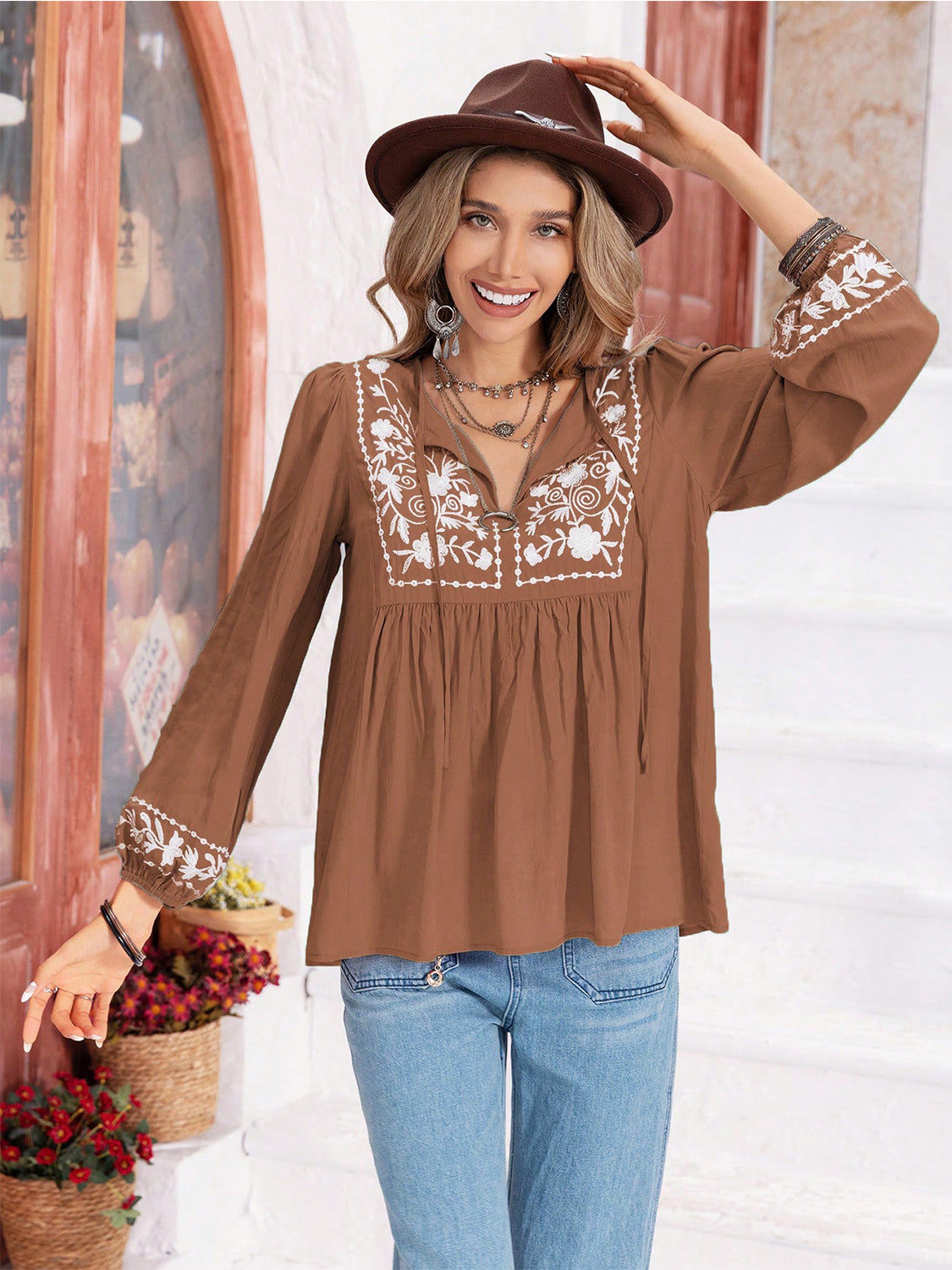 Camel embroidered yoke blouse with gathered bodice and tie neck.