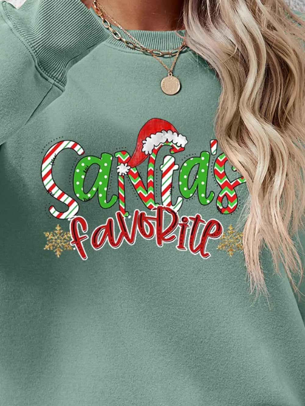 Sage green crewneck sweatshirt with Santa's Favorite festive graphic and snowflakes.