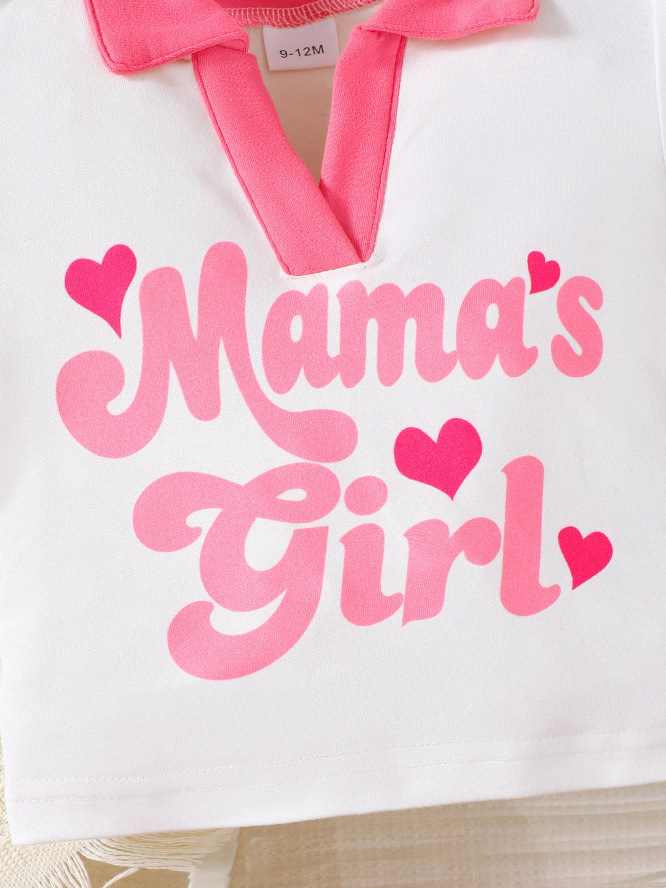 White short sleeve top with pink "Mama's Girl" graphic and pink collar.