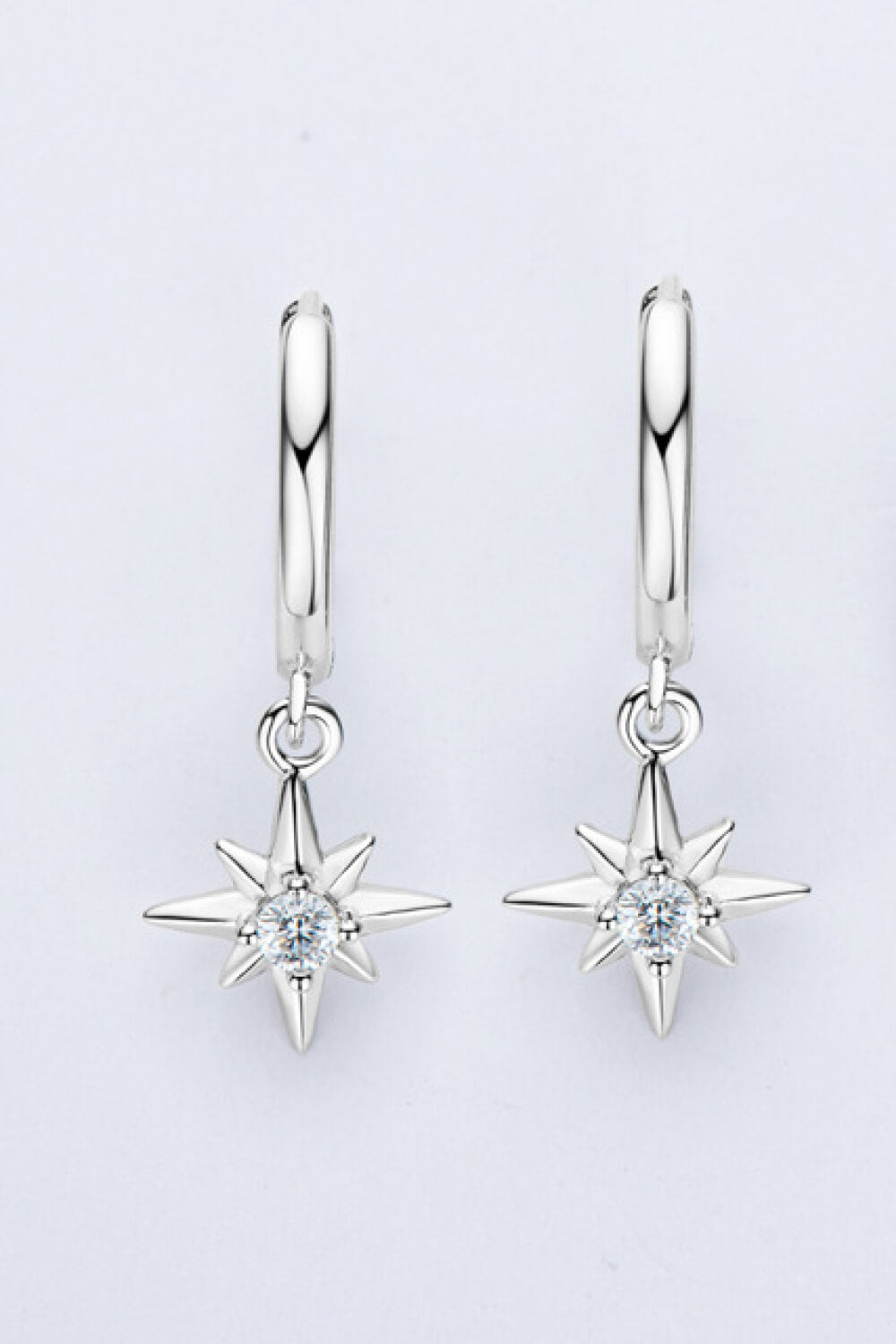 Silver hoop earrings with dangling starburst charms featuring a central crystal.