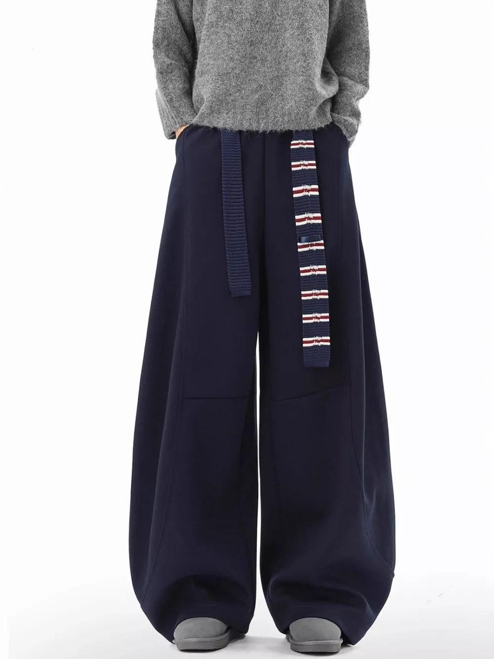 Navy blue ultra-comfort wide-leg sweatpants with a striped belt and grey shoes.