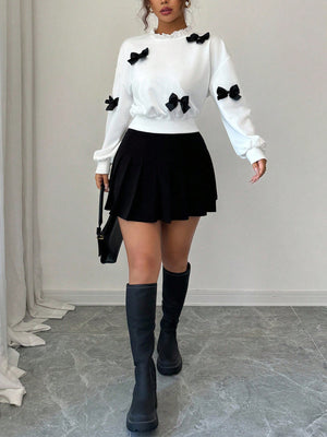 White crew neck sweatshirt with black bow appliques and ruffled neckline.