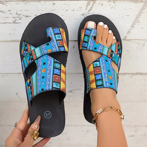 Toe loop sandals with colorful geometric pattern straps and black soles.