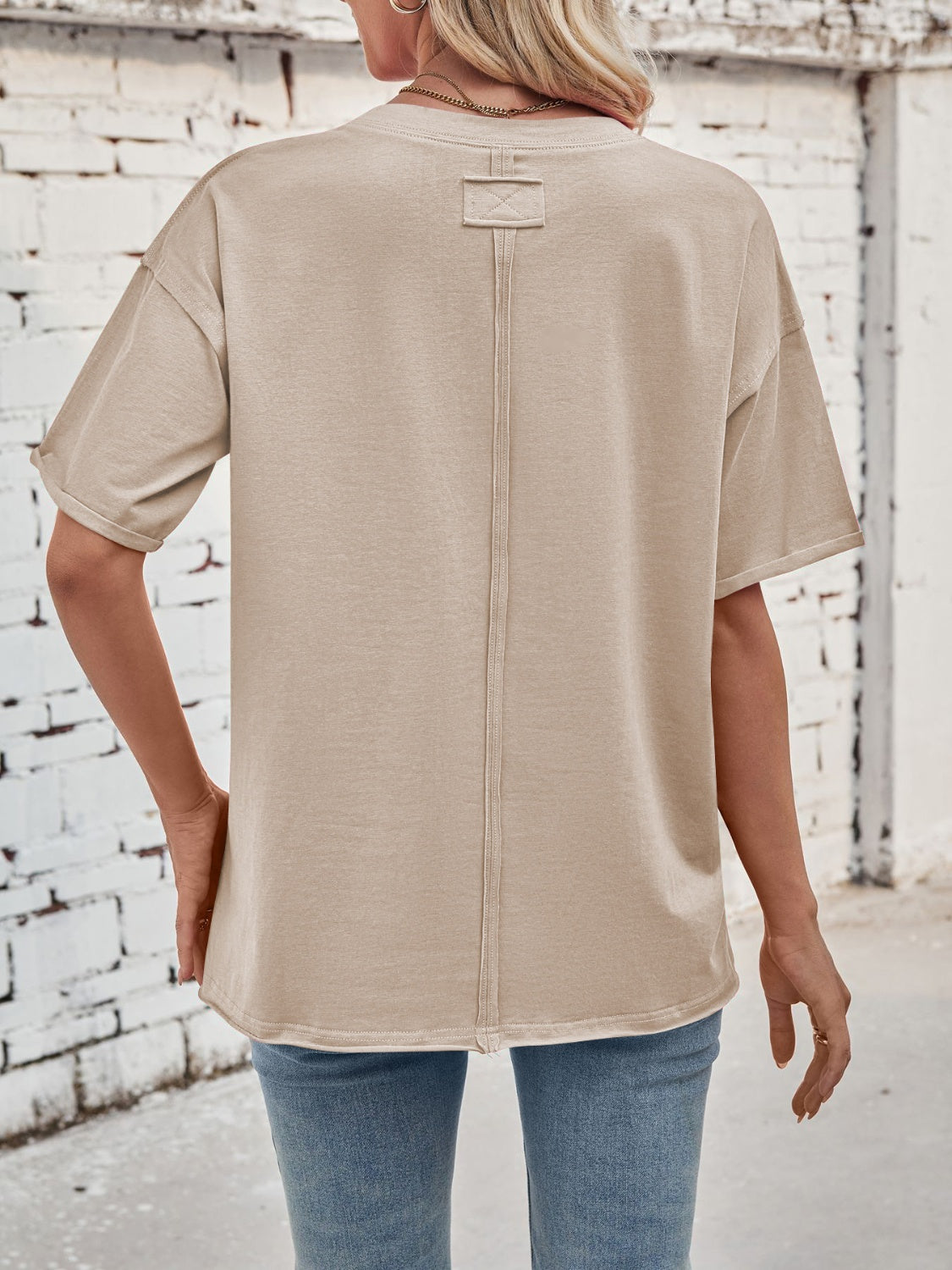 Oversized beige cotton tee with seam detail on back and a tag detail at the neckline.