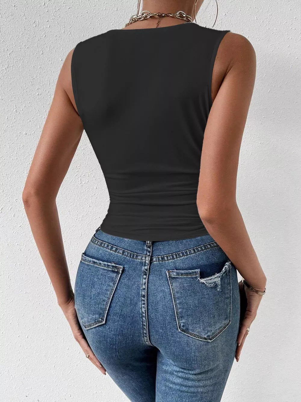 Black ruched cowl neck tank top with a cinched waist, paired with distressed denim jeans.