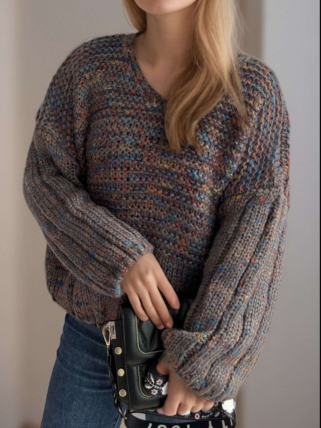 Textured knit sweater in dark gray with multicolor flecks, V-neck, balloon sleeves, and ribbed cuffs.