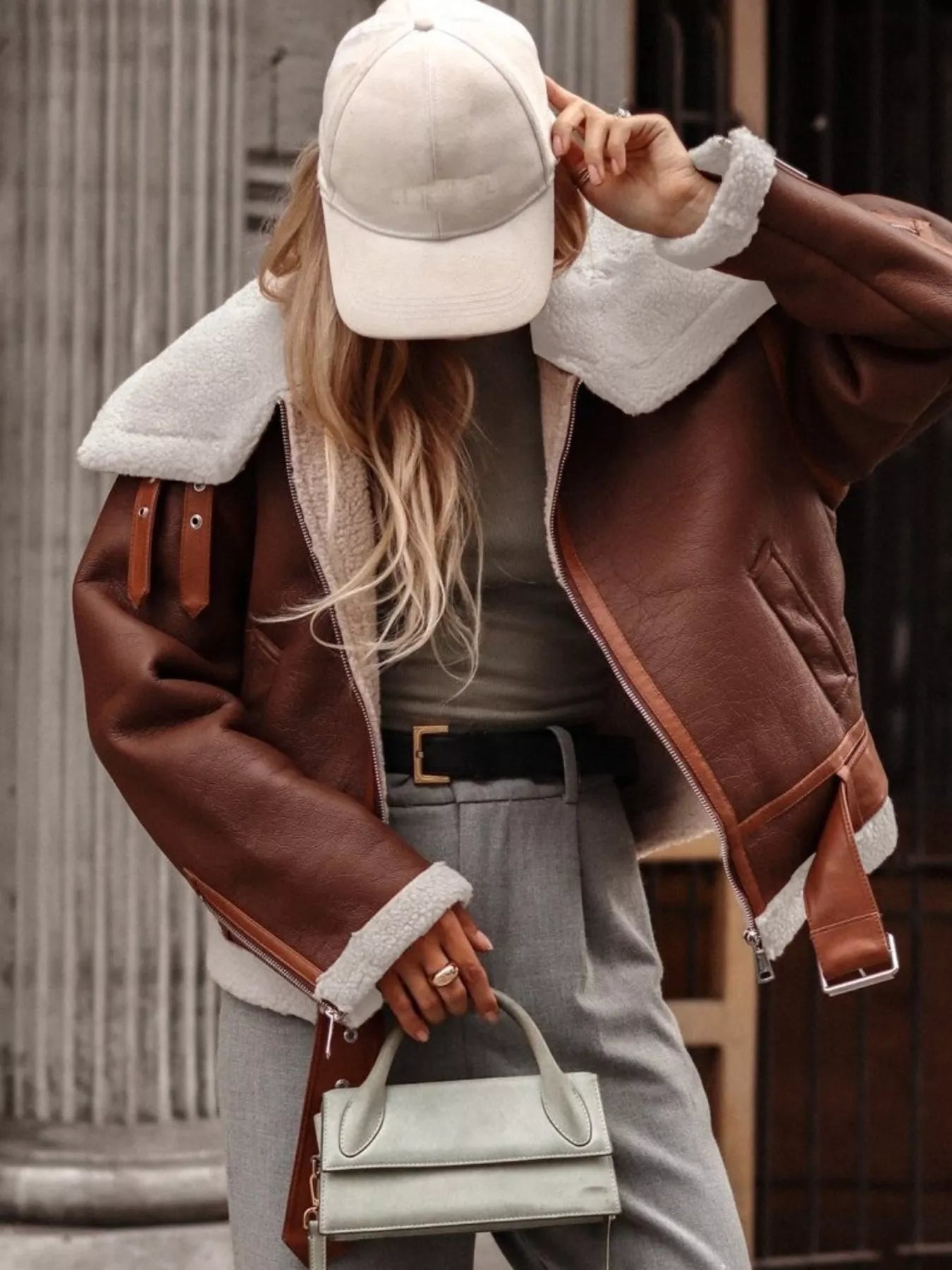 Brown shearling lined zip up jacket with white trim and buckle details.