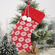 Red cable knit Christmas stocking with white snowflake pattern and pom-poms.