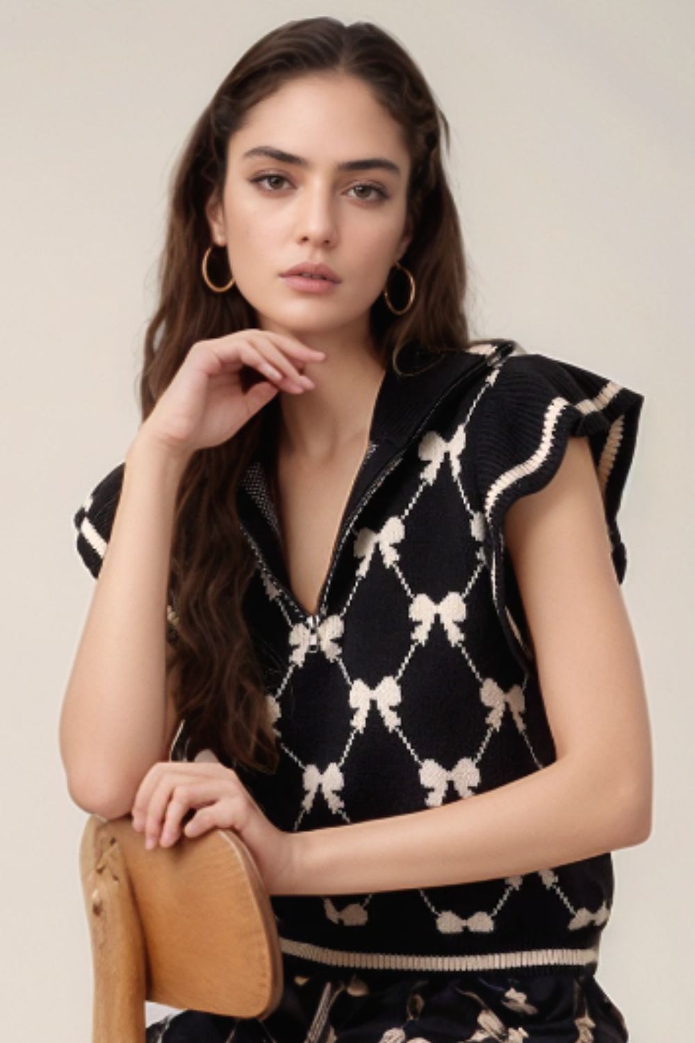 Black knit zip vest with allover bow pattern and contrast trim