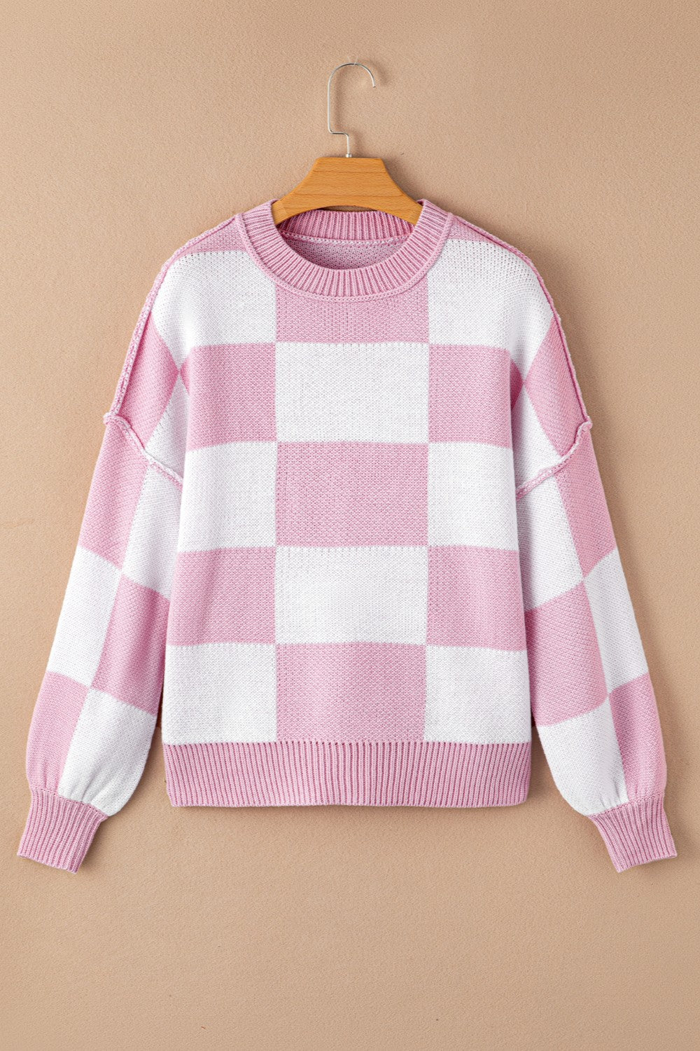 Checkerboard knit crewneck sweater in dusty pink and white with balloon sleeves.