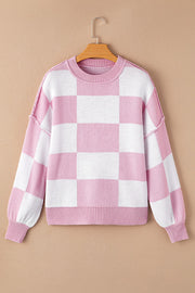 Checkerboard knit crewneck sweater in dusty pink and white with balloon sleeves.