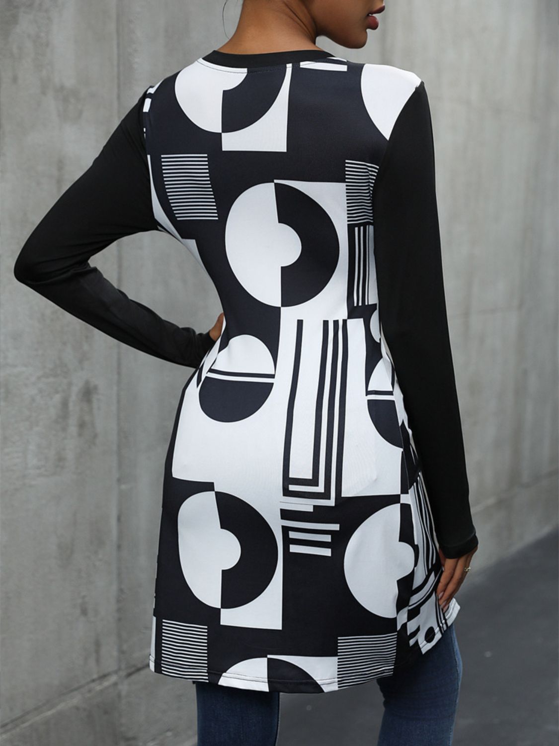 Black tunic top with asymmetric geometric print and long sleeves.
