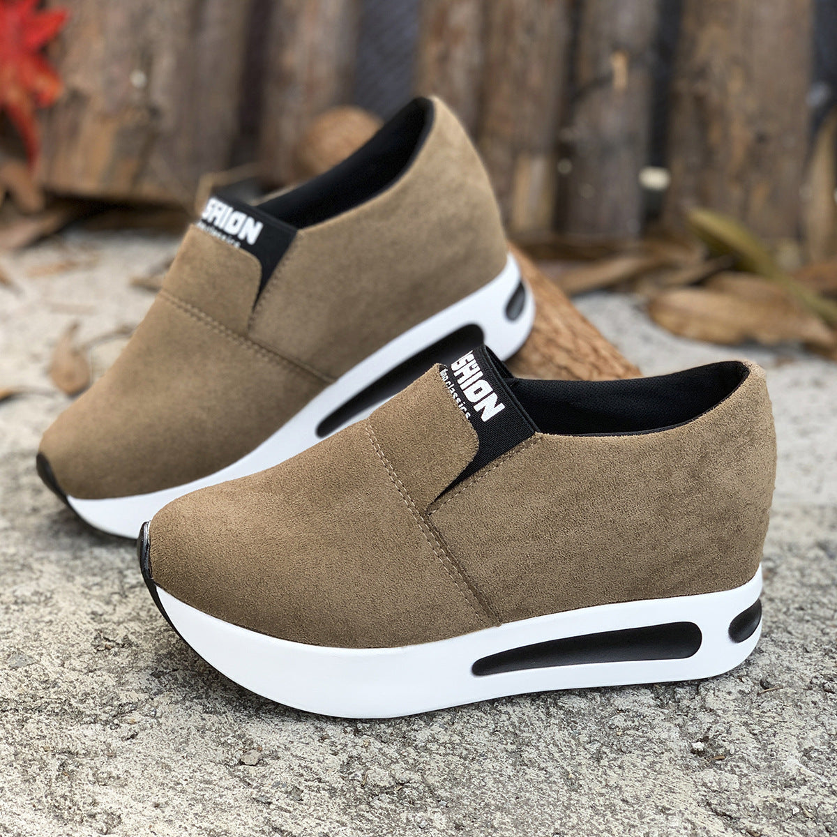 Dark brown round toe slip-on sneakers with white platform soles and black trim.