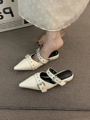 Beige pointed mules with buckle strap detail and silver hardware.