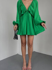 Green ruched V-neck dress with balloon sleeves and a mini hem.