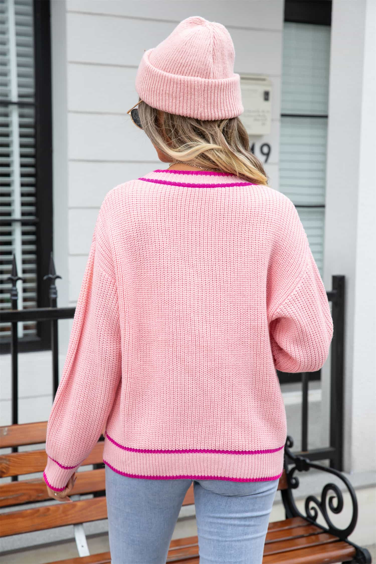 Pink acrylic cardigan with contrast trim and pockets, shown from the back.
