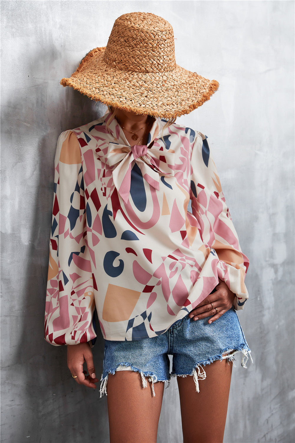 Abstract print pussy bow blouse with balloon sleeves in cream, pink, blue, and maroon.