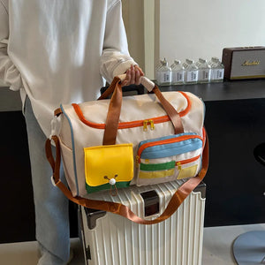 Beige duffel bag with bright colorblock pockets, orange trim, and brown straps.