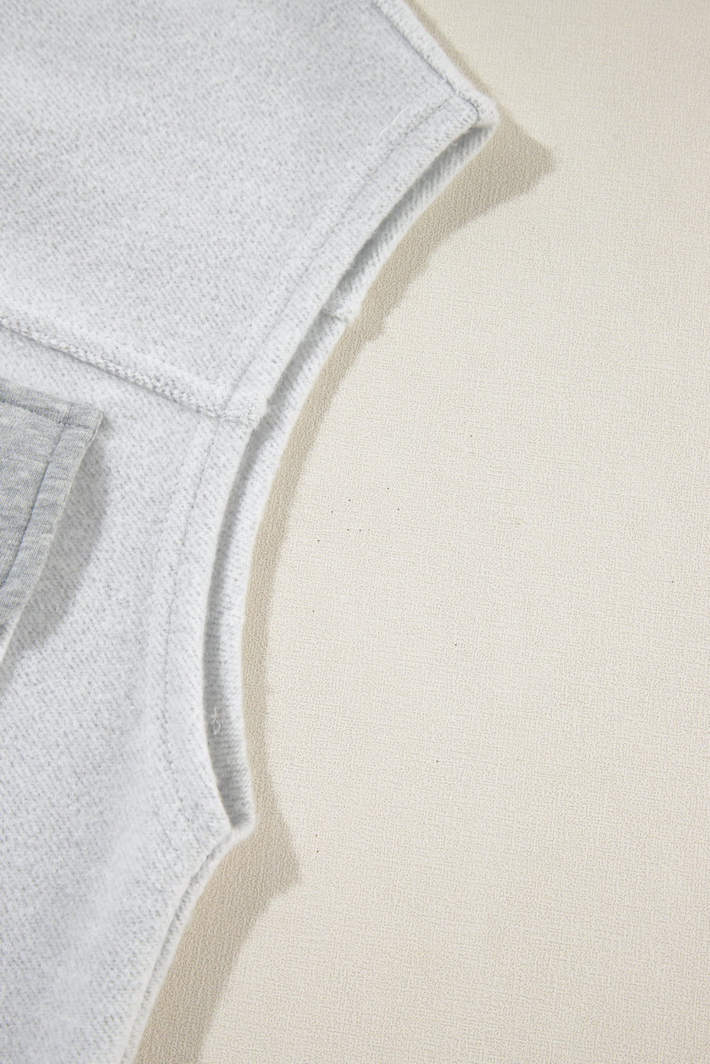 Light gray cotton utility vest detail showing contrast trim and stitching.