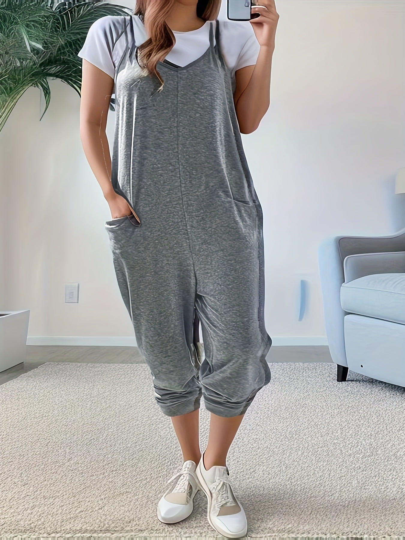 Heathered dark gray loose fit spaghetti strap jumpsuit with pockets, worn over a white tee.