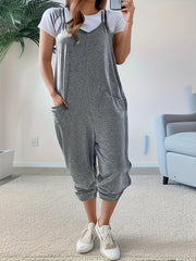 Heathered dark gray loose fit spaghetti strap jumpsuit with pockets, worn over a white tee.