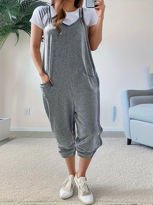 Heathered dark gray loose fit spaghetti strap jumpsuit with pockets, worn over a white tee.