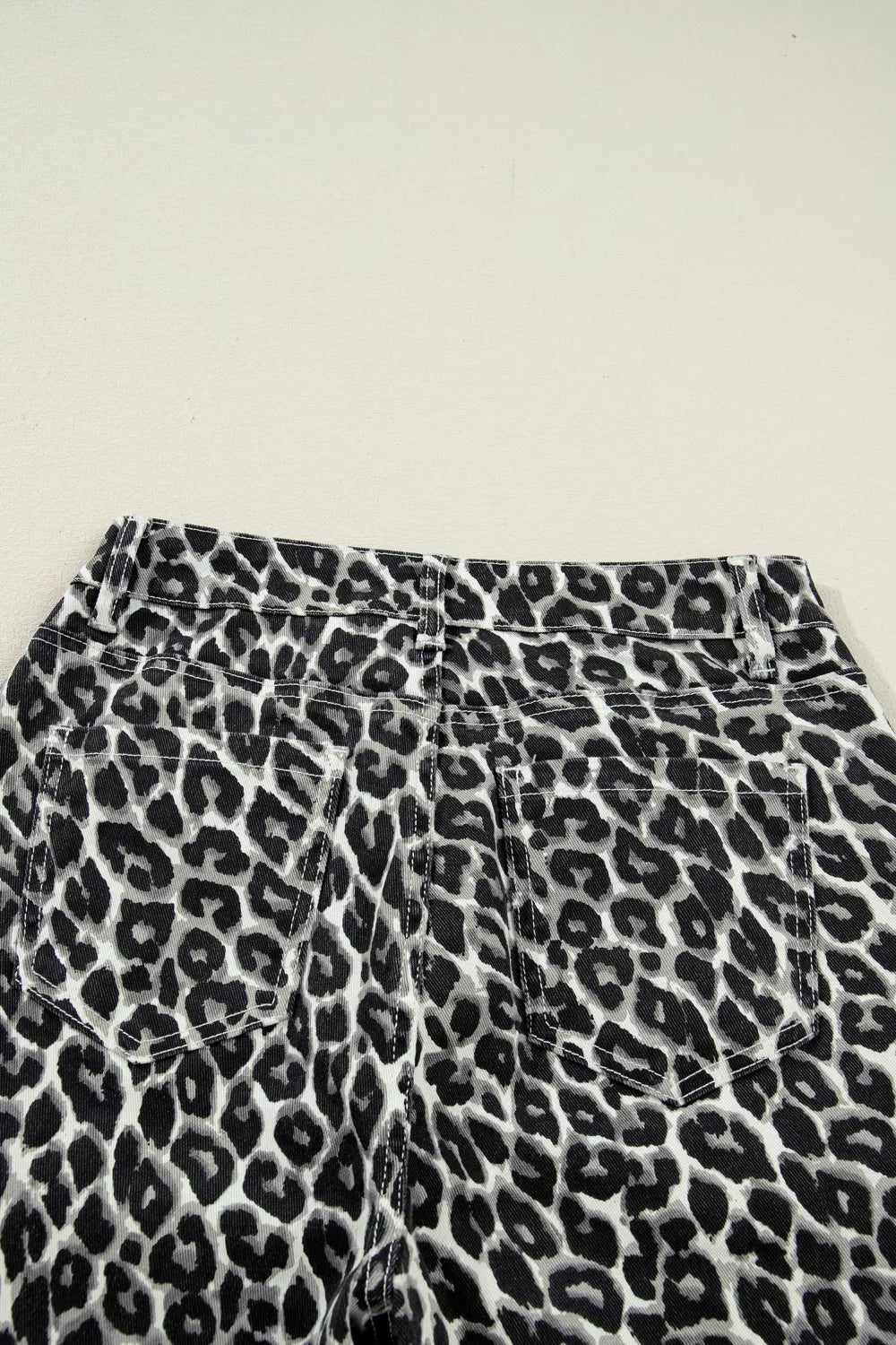 Chic cropped leopard print denim jeans with back pockets and adjustable waist detail.