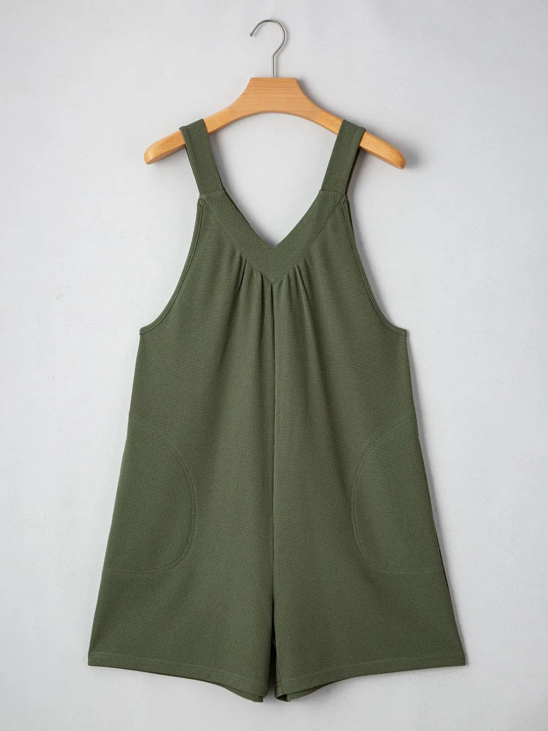 Moss green textured romper with V-neck, gathered yoke, and rounded pockets.