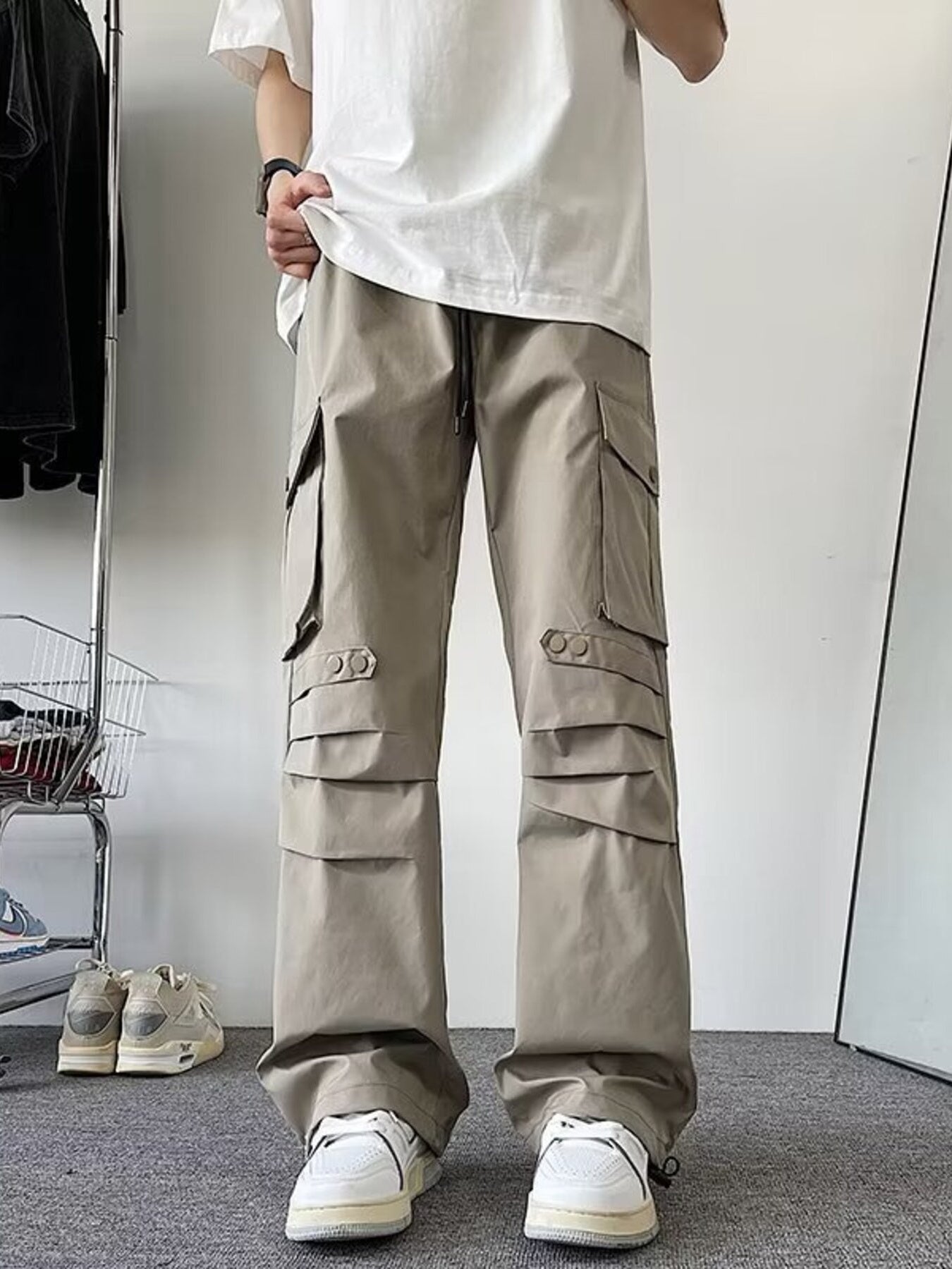 Khaki wide-leg cargo pants with multiple flap pockets and adjustable ankle cuffs.