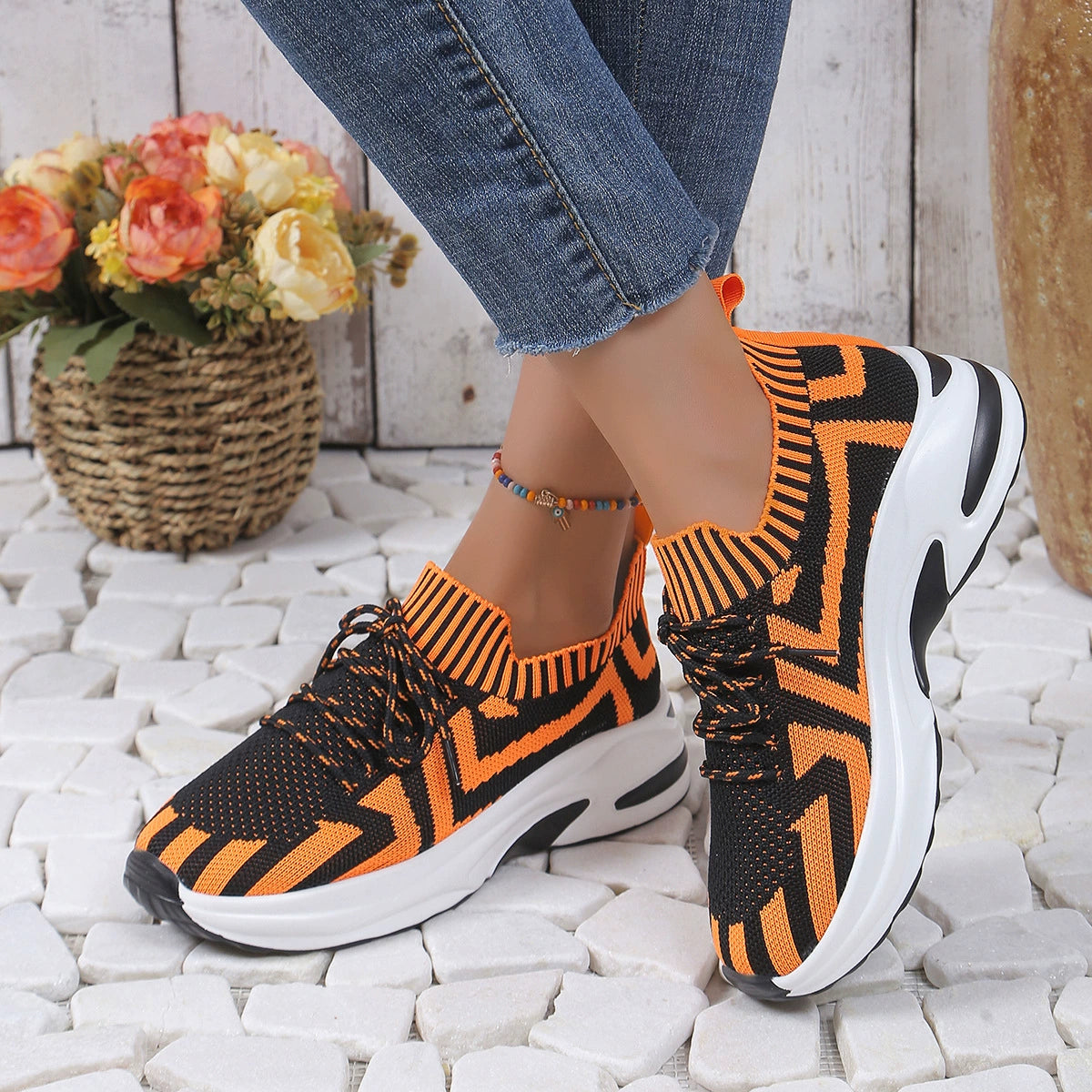 Geometric knit platform sneakers in orange and black with white soles.