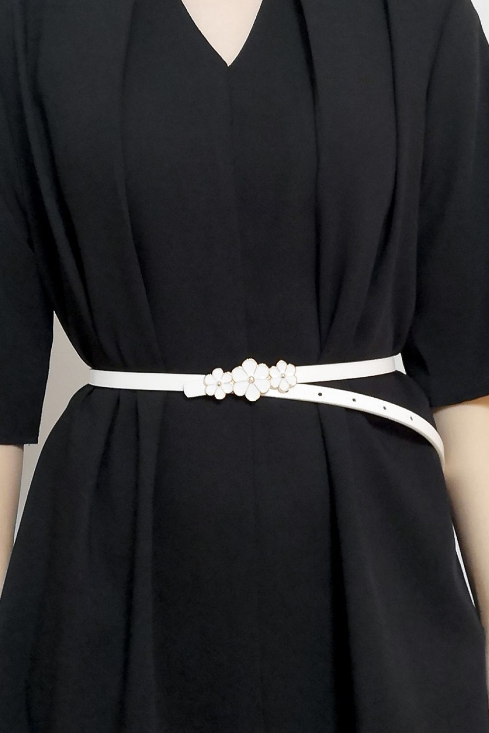 White skinny belt with floral blossom detail cinching a black dress