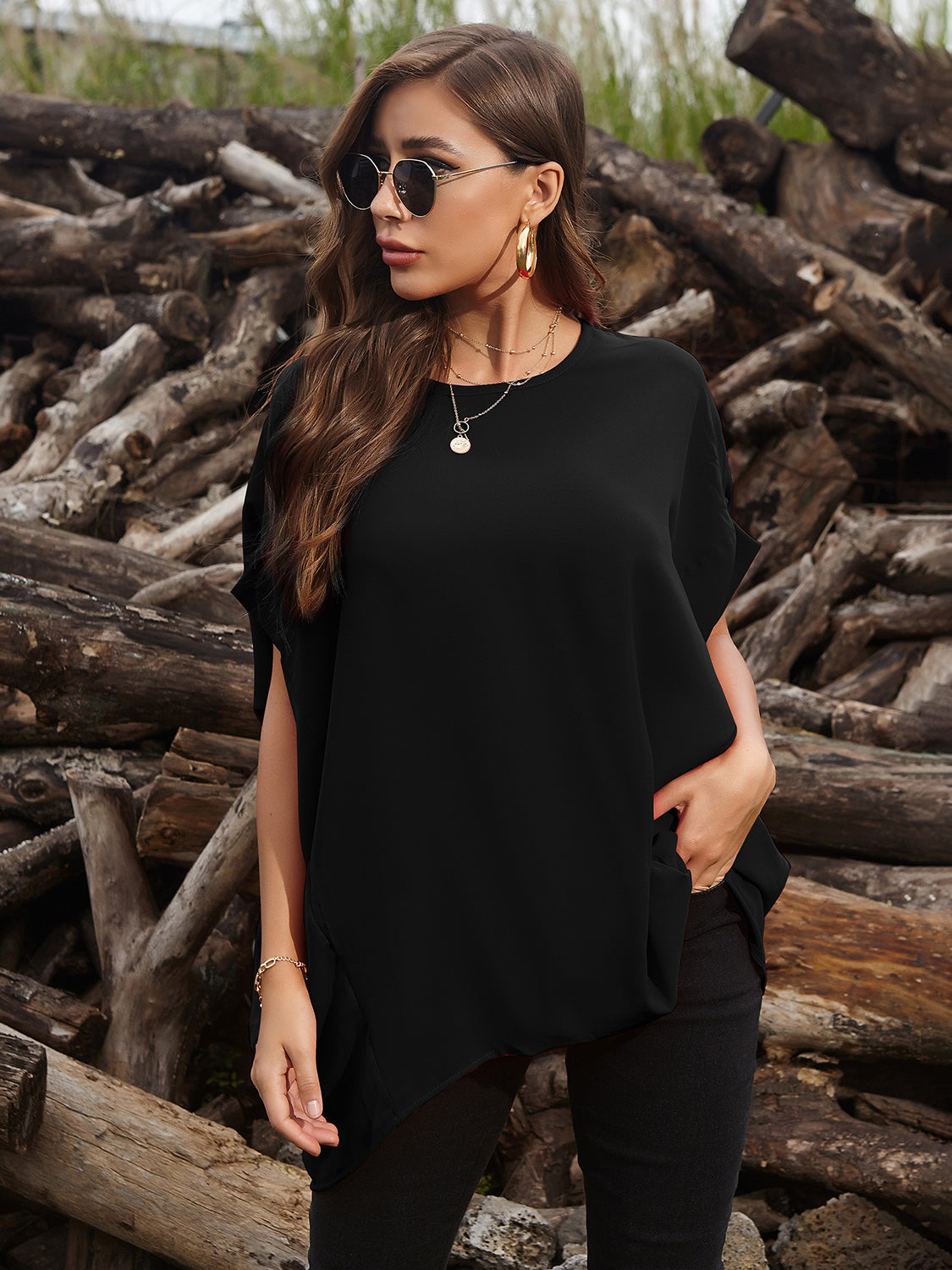 Black draped asymmetrical sleeve blouse with a relaxed fit and crew neck.