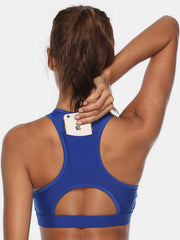 Royal blue racerback sports bra with back pocket holding a phone and cutout detail.
