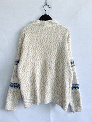 Geometric knit mockneck pullover in an eggshell hue with subtle blue accents on the sleeves.