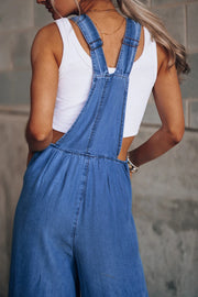 Distressed denim palazzo dungaree jumpsuit in light wash, featuring wide legs and adjustable straps.