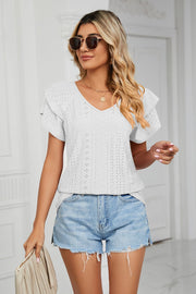 White eyelet knit blouse with flutter sleeves and V-neck, styled with denim shorts.