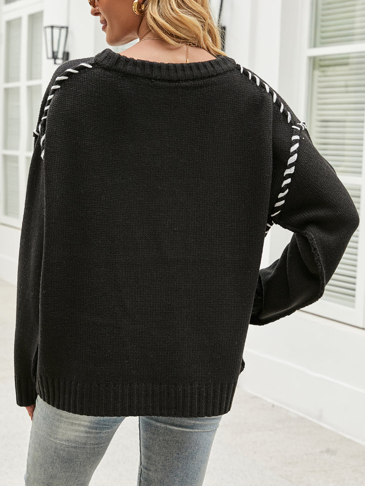Black acrylic knit sweater with contrast white stitching detail on relaxed shoulders and sleeves.