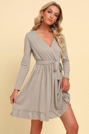 Tan wrap dress with long sleeves, V-neck, tie waist, and ruffled hem.