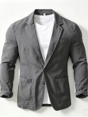 Grey long sleeve blazer with notched lapels, two button closure, and patch pockets, worn over a white t-shirt.