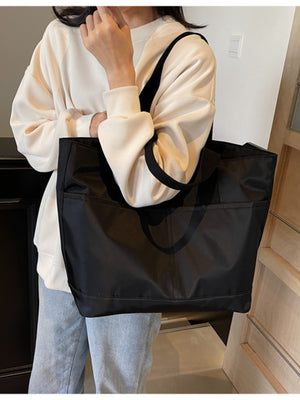 Black Oxford cloth tote bag with exterior pockets and black straps